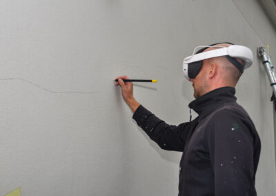 Jetzt sieht Jan durch seine VR-Brille den Entwurf auf der Wand. So kann er die ersten Flächen perfekt anzeichnen.